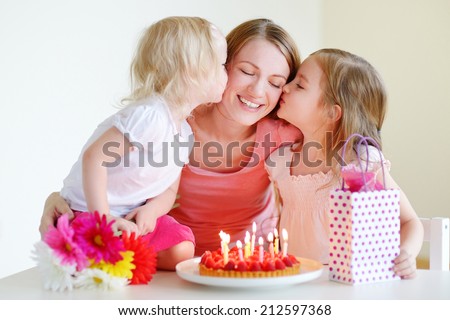 Two little daughters kissing their mother wishing her a happy birthday