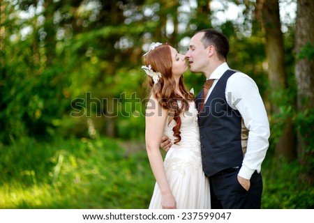 Young bride and groom hugging and kissing in beautiful summer park