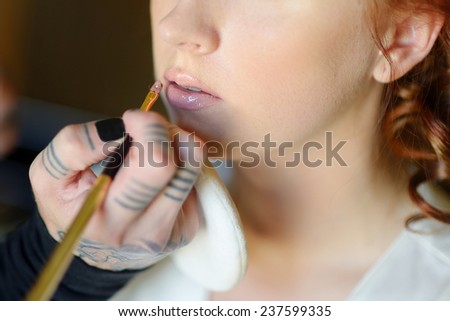 Young beautiful bride applying wedding make-up by professional make-up artist