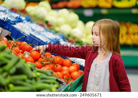 Little girl choosing tomatoes in a food store