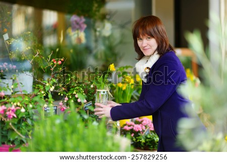 Beautiful young woman selecting flowers at flower market in Paris, France