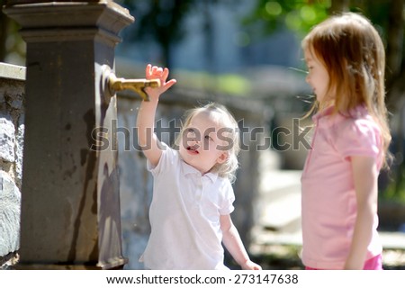 Two sisters having fun with drinking water fountain in Italy