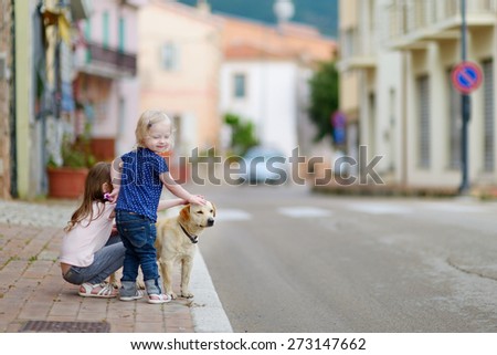 Two cute little sisters and a dog in italian town