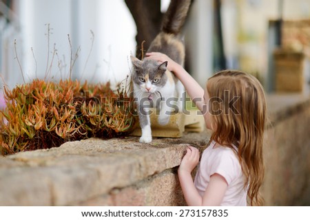 Cute little girl and a cat outdoors on hot summer day in Italy