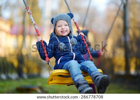 Adorable girl having fun on a swing on beautiful autumn day