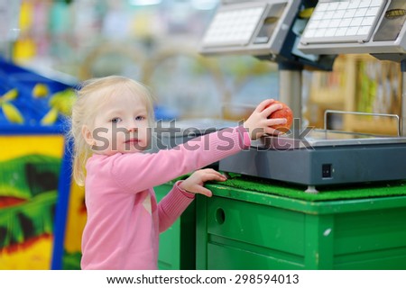 Cute little toddler girl shopping in a food store or a supermarket