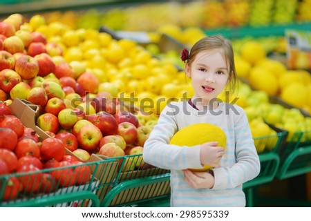 Little girl choosing a melon in a food store or a supermarket
