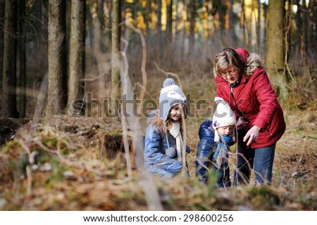 Two adorable sisters and their grandmother taking a walk on autumn forest