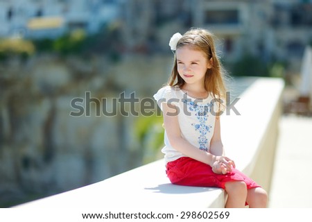 Adorable little girl on warm and sunny summer day in typical italian town