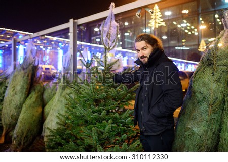 Young man buying a Christmas tree in the store