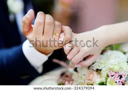 Bride and groom holding their hands with wedding rings on fingers