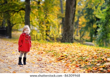 Little girl in a red coat at autumn