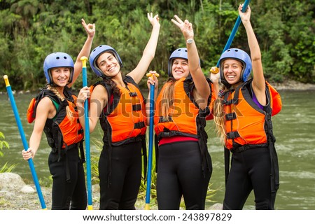 GROUP OF FOUR YOUNG LADIES PREPARED TO GO WHITE WATER RAFTING, WEARING SPECIFIC EQUIPMENT