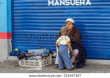 Salasaca, Ecuador - 24 January 2014: Emotional Moment With A Street Seller Woman Giving Attention To Her Young Son In Salasaca On January 24, 2014
