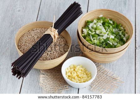 Ingredients for an Asian dish: rice noodles, spring onions, sesame and ginger.