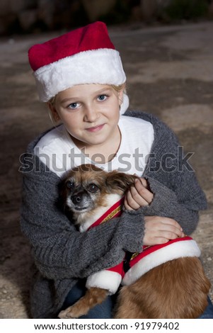 Girl dressed in christmas hat holding a dog with christmas costume