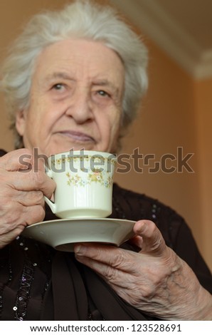 senior woman holding a cup of tea in order to drink