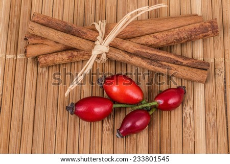 rose hip fruit and cinnamon sticks on wooden surface