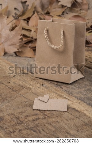 paper shopping bag and dried leafs on wooden surface