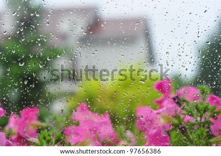Drops of rain on a window pane, house and garden in background