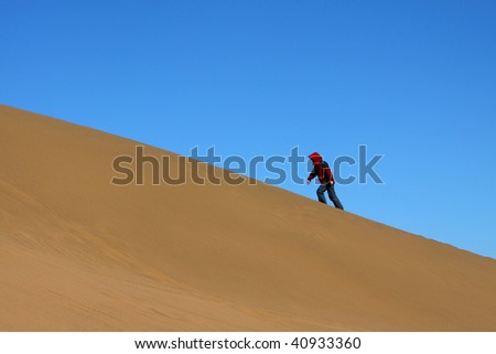 The lady in red is ascending the sand hill in Ba Dan Ji Lin desert, Inner Mongolia, China