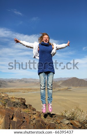 The jumping smiling girl against a mountain landscape in mongolia