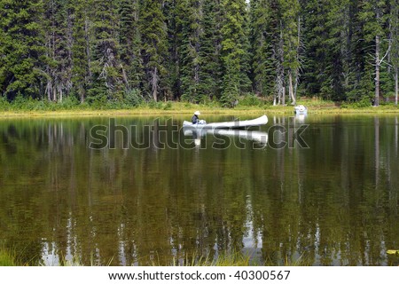 Mirror lake & a white canoe fisherman