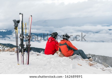 Two young men skiers sitting on snow covered hill