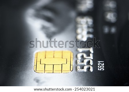 A closeup view of a credit card, dark black card with white numbers, chip in detail