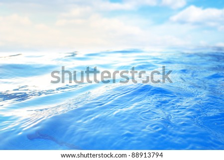 Blue water waves in a swimming pool, reflects the blue sky and white clouds, looks like blue ocean waves