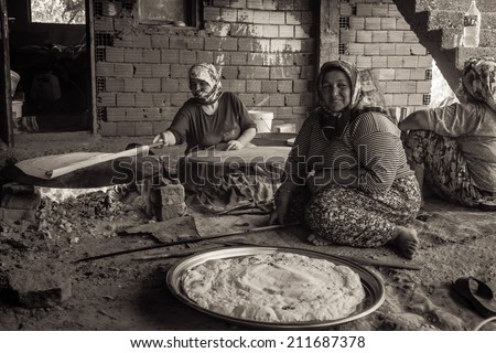 EVRENLERYAVSI, TURKEY - JUNE 24, 2014: Village women prepare traditional flatbread on an open fire. Sepia