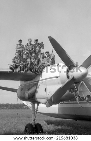 MOSCOW REGION, RUSSIA - CIRCA 1993: A group of soldiers standing on the wing of a military transport aircraft AN-24. Film scan. Large grain, circa 1993