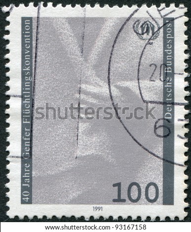 GERMANY - CIRCA 1991: A stamp printed in Germany, dedicated to 40th anniversary of the Geneva Convention on Refugees, shows a hand holding cloak and emblem, circa 1991