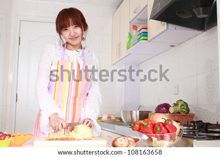 A Chinese woman is cooking on a chopping block with various kinds vegetable.