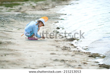 girl in a cap on the beach with a net draws on the beach