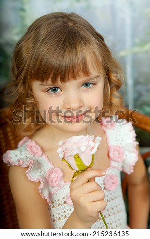Portrait of beautiful girl in fishnet jersey dress in a wicker chair with a flower