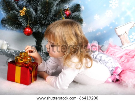 beautiful girl with a gift lies near the Christmas tree