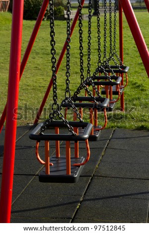 A row of swing seats on metal chains with safety bars and a protective padded floor.