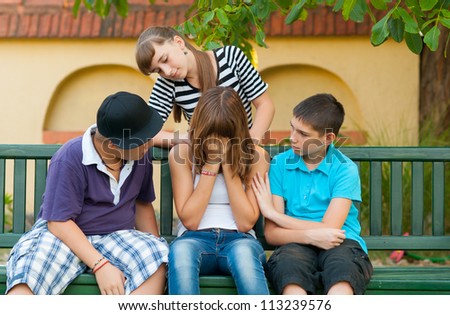 Teenage friends consoling and supporting their crying girlfriend.