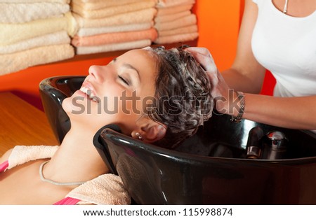 Beautiful young girl enjoying hair washing in hairdressing salon.