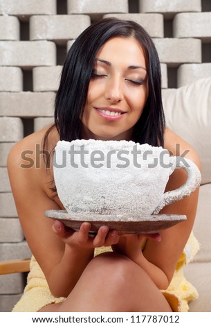 Beautiful smiling girl sitting in the salt room and inhaling sea salt from huge salt bowl during salt therapy.