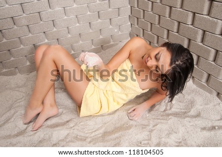 Beautiful sexy smiling girl lying in the salt room during salt therapy.