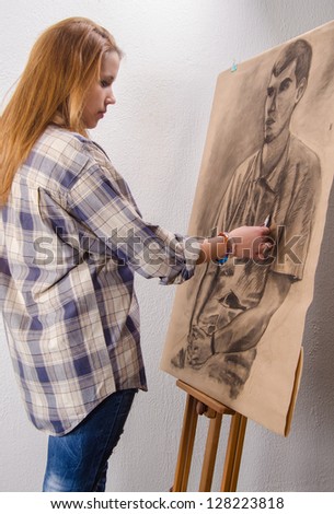 Young female artist drawing man portrait in her art studio.