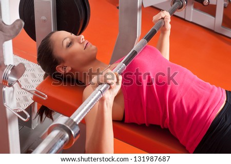 Beautiful smiling young woman exercising with weights in the gym.