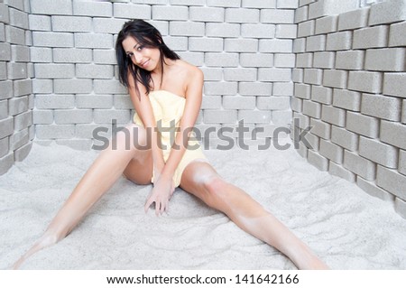 Beautiful sexy smiling girl enjoys sitting in the salt room during salt therapy.