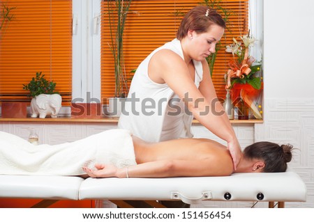 Young massage therapist giving a massage in massage salon.