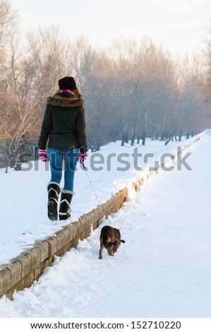 Teenage girl walking the dog on cold winter day.