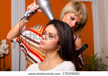 Hairdresser making hair of beautiful happy girl.