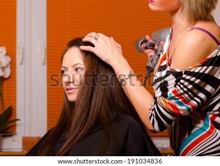 Hairdresser making hair of beautiful happy girl.