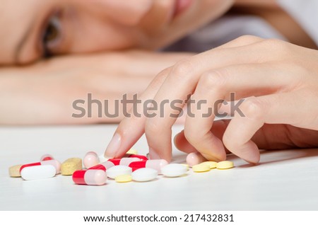 Unhappy woman touching pills and capsules.